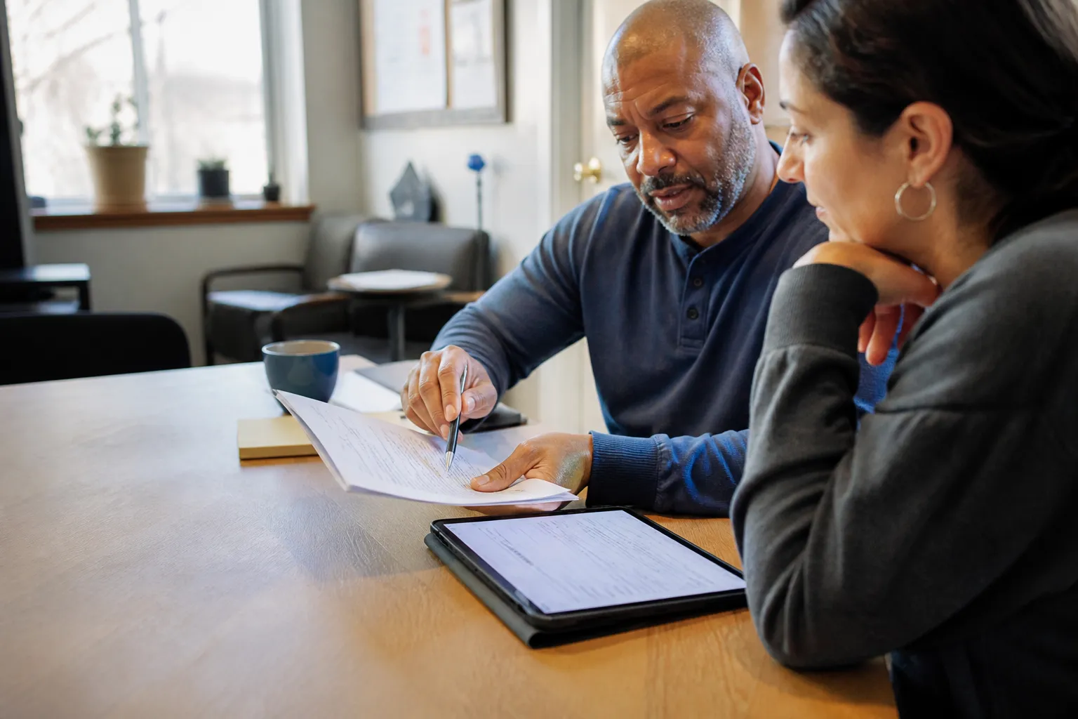 Two people reviewing an intake packet and tablet together during a working consultation